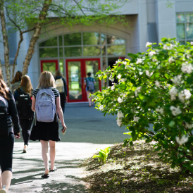 Students walking into a building with red doors